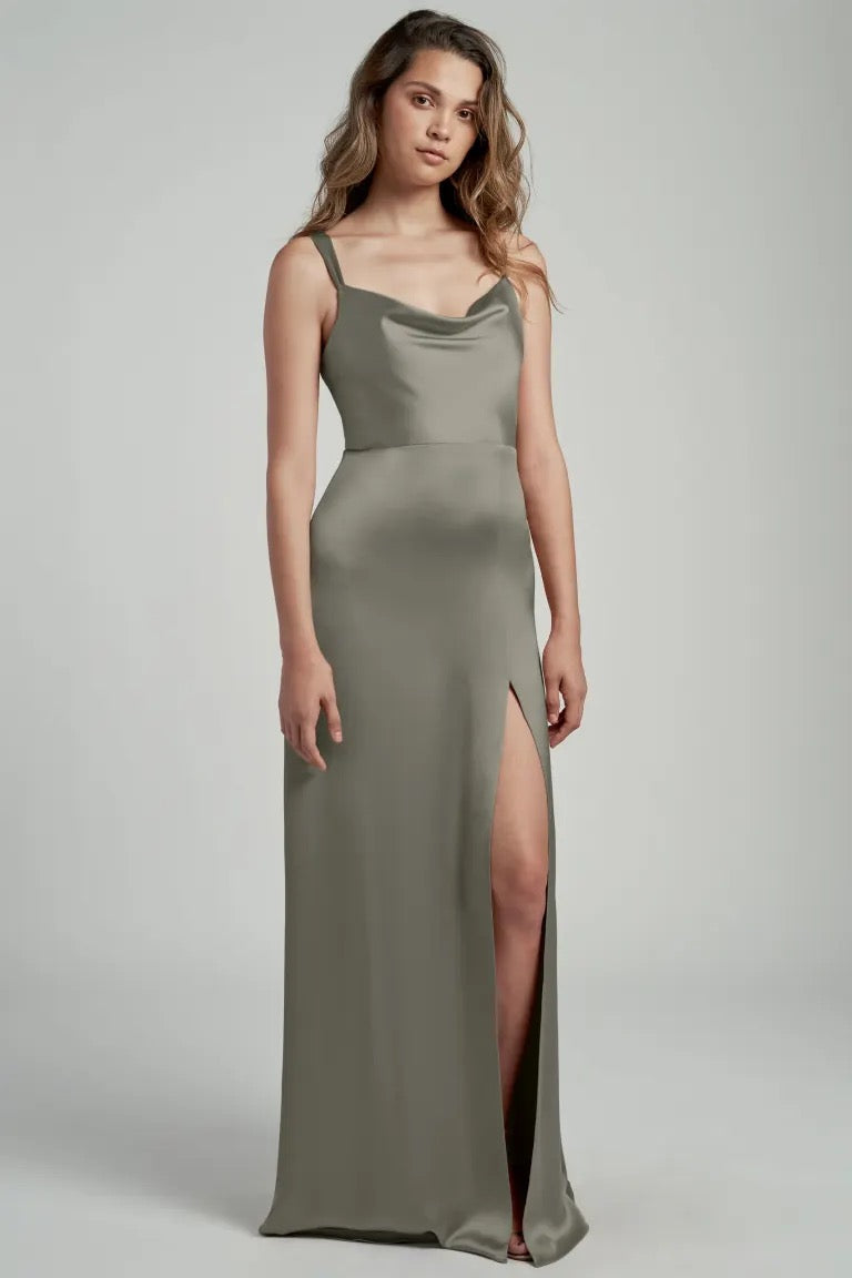 Woman posing in an elegant olive green satin bridesmaid Gina dress by Jenny Yoo with a thigh-high slit and cowl neckline from Bergamot Bridal.