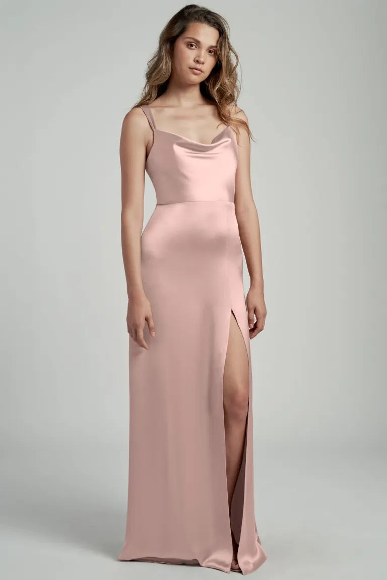 Woman in a pink satin bridesmaid dress with a cowl neckline and thigh-high slit, the Gina Bridesmaid Dress by Jenny Yoo from Bergamot Bridal.