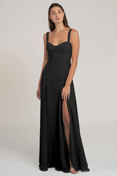 Woman in a black sleeveless evening gown with a high leg slit and a flattering silhouette, the Harris Bridesmaid Dress by Jenny Yoo from Bergamot Bridal.