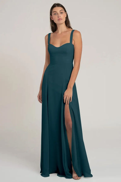 Woman in an elegant green chiffon bridesmaid dress with a high slit and a bombshell neckline - Harris Bridesmaid Dress by Jenny Yoo from Bergamot Bridal.