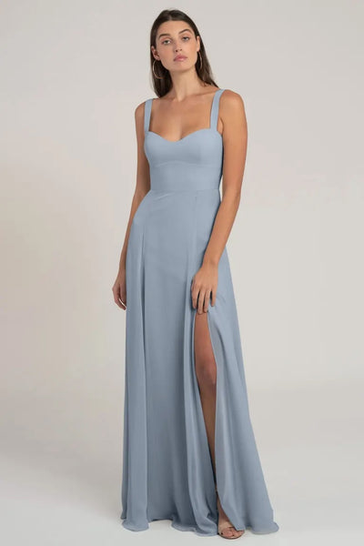 A woman models a light blue, chiffon Harris bridesmaid dress by Jenny Yoo with a bombshell neckline and a high slit from Bergamot Bridal.