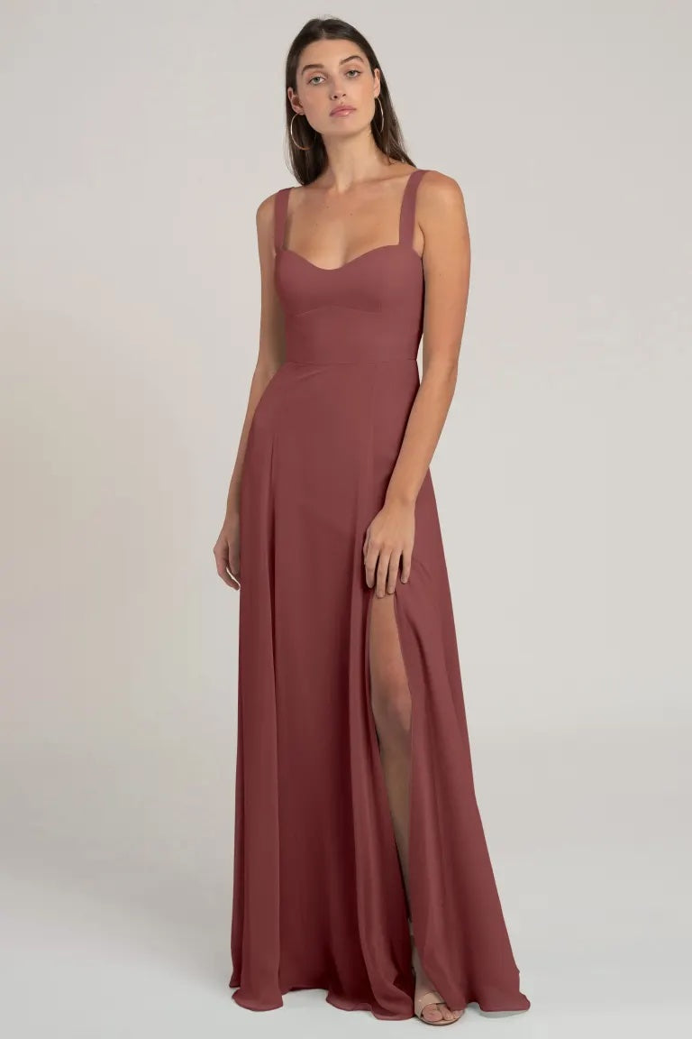 Woman in a sleeveless mauve chiffon evening gown with a high leg slit, designed in a flattering silhouette - Harris Bridesmaid Dress by Jenny Yoo from Bergamot Bridal.