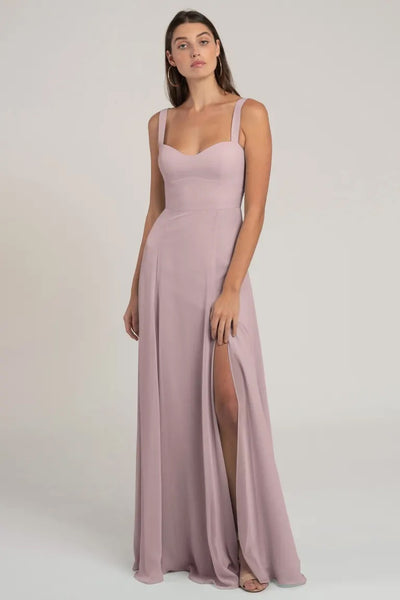 A woman wearing a light pink chiffon bridesmaid dress with a sweetheart neckline and a thigh-high slit, the Harris Bridesmaid Dress by Jenny Yoo from Bergamot Bridal.
