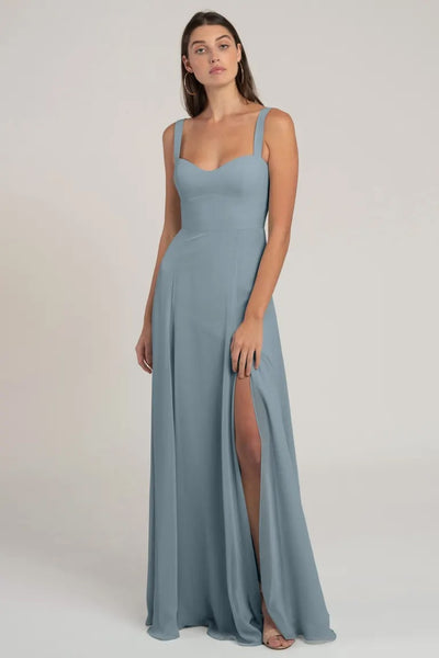 Woman posing in a light blue chiffon Harris bridesmaid dress by Jenny Yoo with a thigh-high slit and a flattering silhouette from Bergamot Bridal.