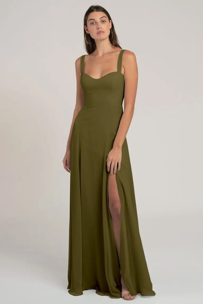 Woman posing in a Harris Bridesmaid Dress by Jenny Yoo from Bergamot Bridal, an olive green chiffon evening gown with a high slit.
