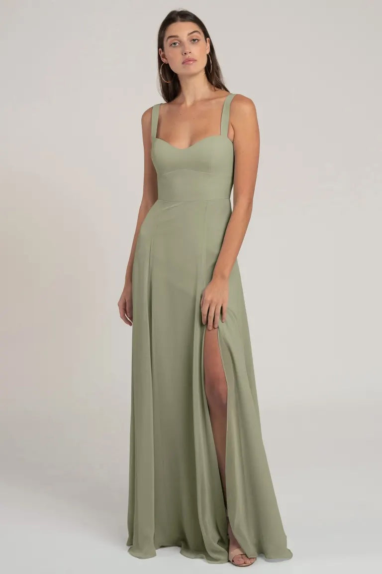 Woman posing in a flattering silhouette, long sage green chiffon bridesmaid dress with a high slit and sweetheart neckline, Harris - Bridesmaid Dress by Jenny Yoo from Bergamot Bridal.