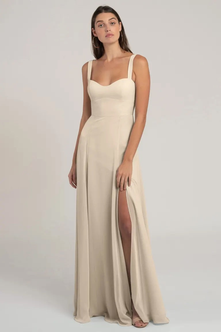 A woman in an elegant beige evening gown with a sweetheart neckline and a thigh-high slit, boasting a flattering silhouette, Harris - Bridesmaid Dress by Jenny Yoo from Bergamot Bridal.