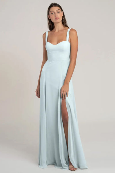 Woman in a light blue chiffon evening gown with a thigh-high slit and a flattering silhouette, wearing the Harris Bridesmaid Dress by Jenny Yoo from Bergamot Bridal.