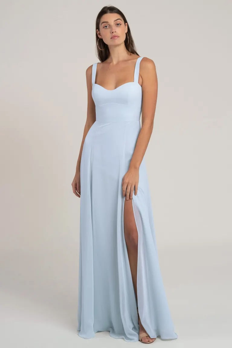 Woman posing in a Harris - Bridesmaid Dress by Jenny Yoo from Bergamot Bridal, a pale blue chiffon evening gown with a thigh-high slit and sweetheart neckline.
