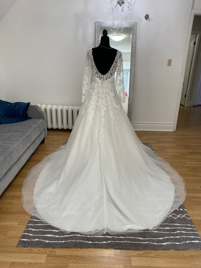 A Bridalane A-line Lace Long Sleeve Dress - Off The Rack with an illusion high neckline and lace details on a mannequin in a living room setting.
