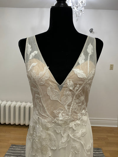 Close-up of a mannequin displaying an elegant sleeveless wedding dress with a v-neckline and detailed white floral motifs by Willowby by Watter Honor 52122 - Sample Size from Bergamot Bridal.