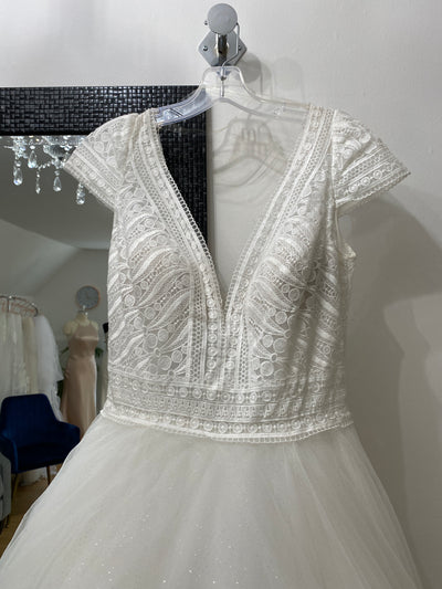 A Allure Disney Wedding Dress - Rapunzel - Off The Rack with a lace bodice and beadwork on a hanger against a Bergamot Bridal boutique backdrop.