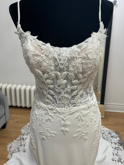 The Bergamot Bridal Crepe and Lace Fit & Flare Gown features a lace train, beaded spaghetti straps, and elegant floral embroidery on the bodice, displayed here on a mannequin.