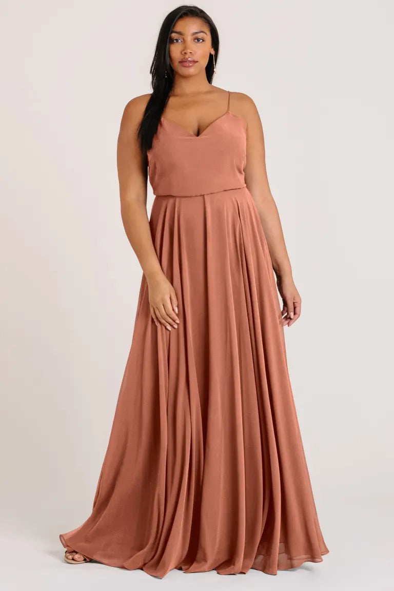 Woman in an elegant rust-colored Inesse bridesmaid dress by Jenny Yoo with a V-neck from Bergamot Bridal.