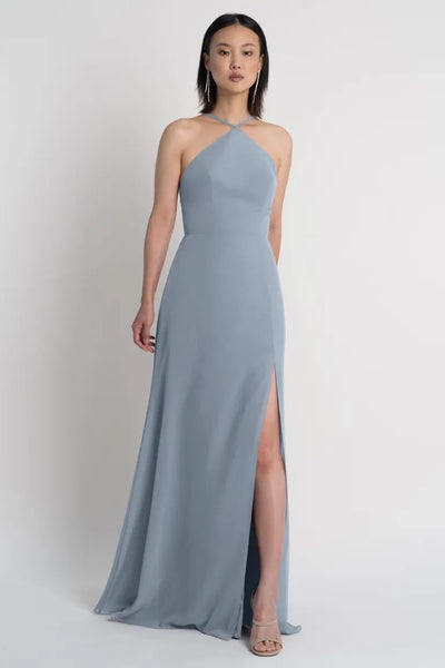 Woman modeling the Ingrid bridesmaid dress by Jenny Yoo featuring a long grey pointed halter neckline with a side slit from Bergamot Bridal.