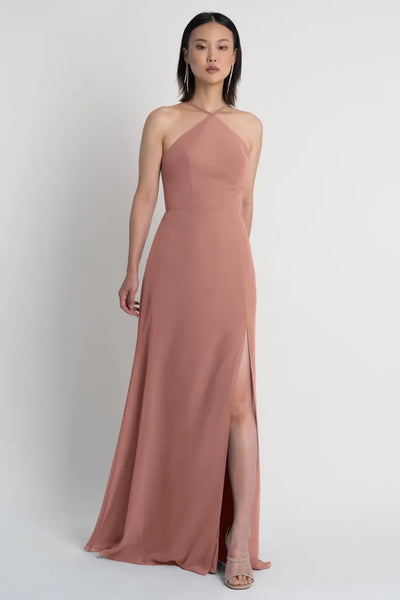 A woman in an elegant, Ingrid bridesmaid dress by Jenny Yoo with a halter neckline and a side slit from Bergamot Bridal.