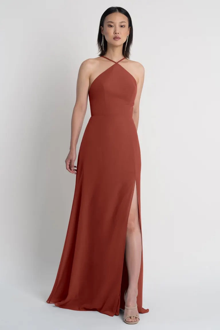 Woman in an elegant rust-colored Ingrid bridesmaid dress by Jenny Yoo with a thigh-high side slit from Bergamot Bridal.