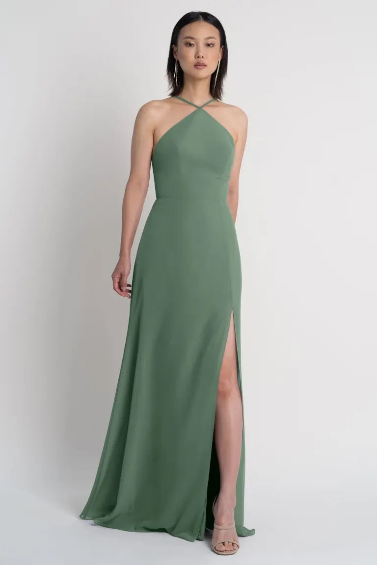 Woman in an elegant green Ingrid bridesmaid dress by Jenny Yoo with a thigh-high side slit from Bergamot Bridal.