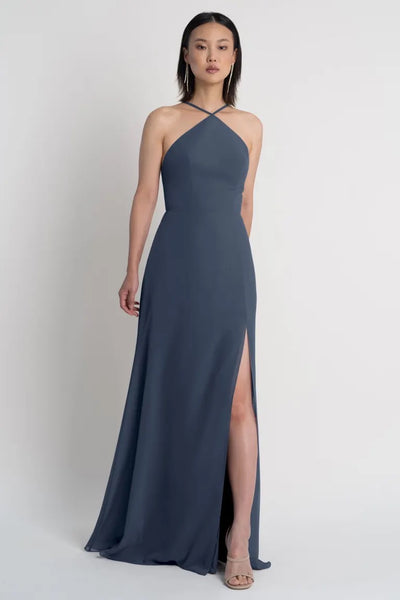 A woman wearing an elegant Ingrid bridesmaid dress by Jenny Yoo with a halter neckline and side slit from Bergamot Bridal.