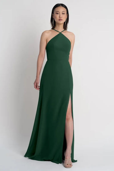 A woman in an elegant green Ingrid bridesmaid dress by Jenny Yoo with a high side slit from Bergamot Bridal.