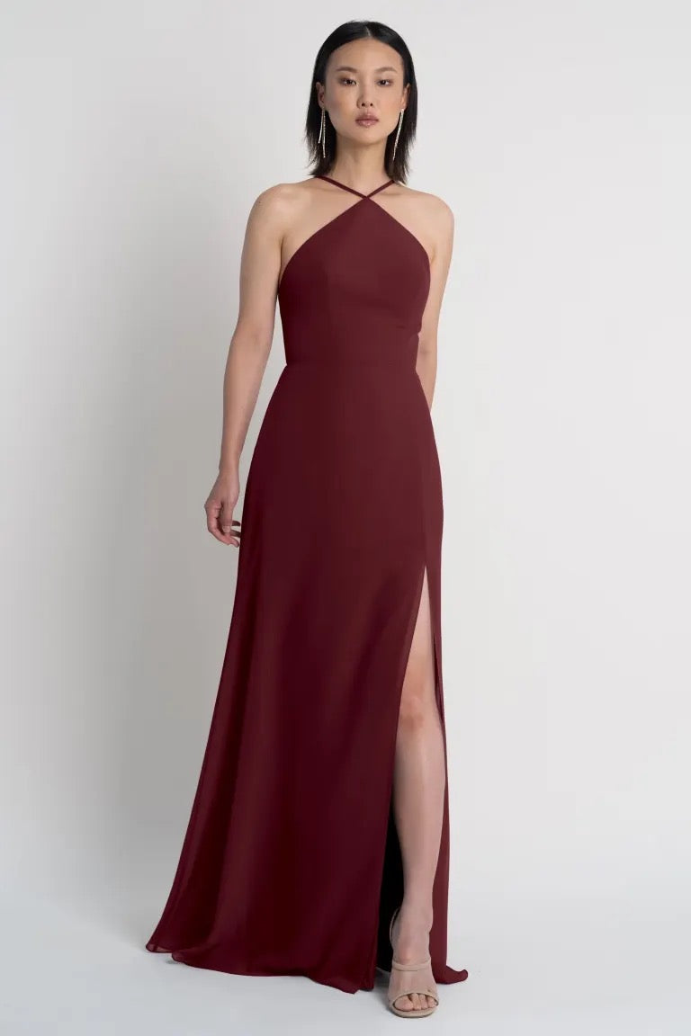 A woman wearing a Jenny Yoo Ingrid bridesmaid dress with a halter neckline and a side slit from Bergamot Bridal.
