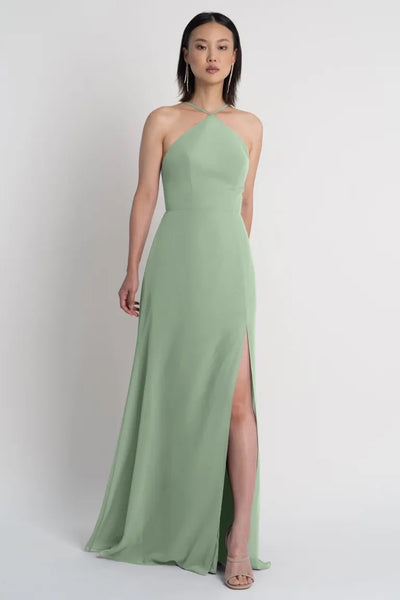 A woman in an elegant sage green Ingrid bridesmaid dress by Jenny Yoo with a side slit from Bergamot Bridal.