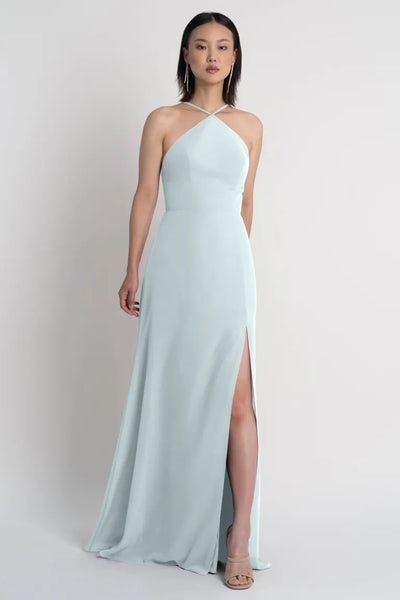 Woman posing in a light blue halter neckline gown with a side slit, the Ingrid bridesmaid dress by Jenny Yoo from Bergamot Bridal.