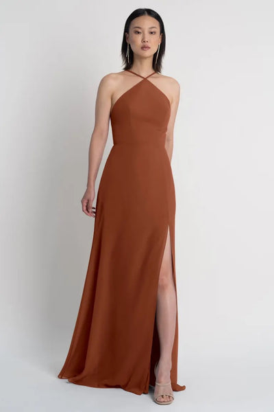 A woman in a rust-colored Ingrid bridesmaid dress by Jenny Yoo with a thigh-high side slit from Bergamot Bridal.