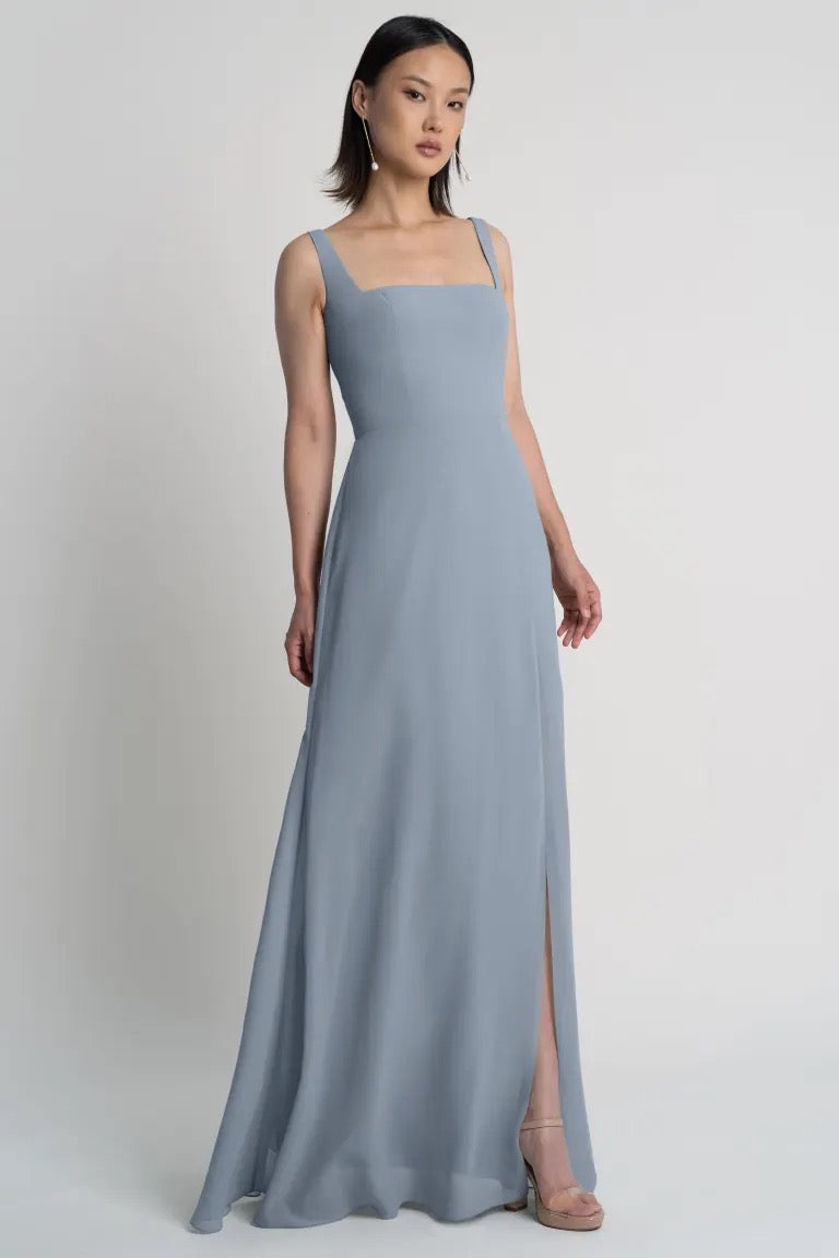 A woman in a sleek, sleeveless Jenna chiffon bridesmaid dress by Jenny Yoo with a square neckline and a subtle flare from Bergamot Bridal.