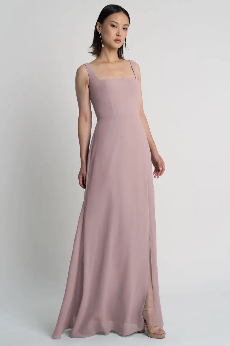 Woman posing in a Jenna - Bridesmaid Dress by Jenny Yoo in pastel pink with a square neckline from Bergamot Bridal.