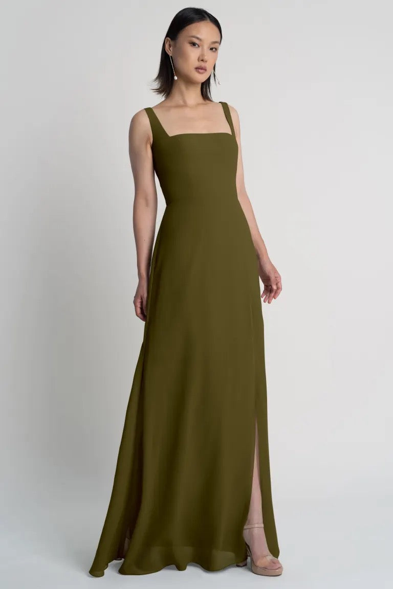 A woman in an elegant Jenna chiffon bridesmaid dress by Jenny Yoo with a square neckline, posing against a neutral background from Bergamot Bridal.