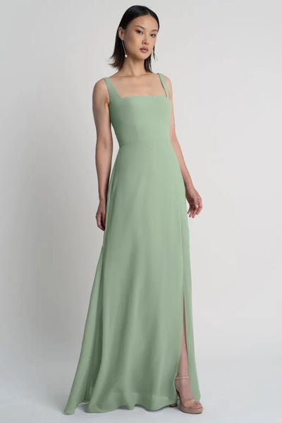 A woman modeling a Jenna bridesmaid dress by Jenny Yoo in mint green with a square neckline from Bergamot Bridal.
