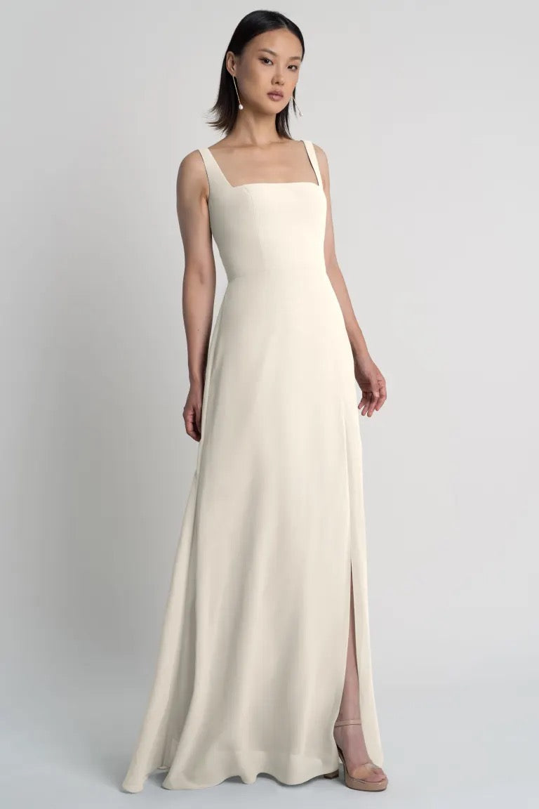 Woman posing in an elegant, sleeveless, chiffon bridesmaid dress with a square neckline and an A-line skirt. Jenna - Bridesmaid Dress by Jenny Yoo at Bergamot Bridal.