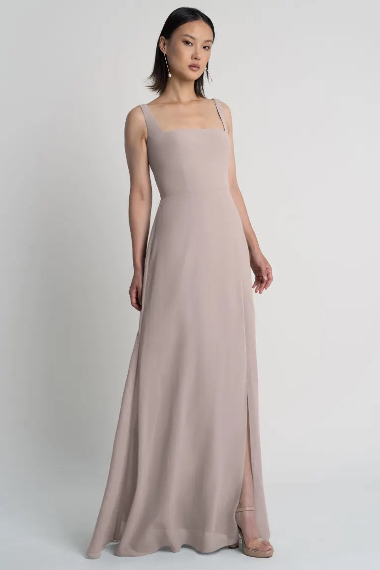Woman posing in an elegant Jenna - Bridesmaid Dress by Jenny Yoo chiffon evening gown with a square neckline from Bergamot Bridal.