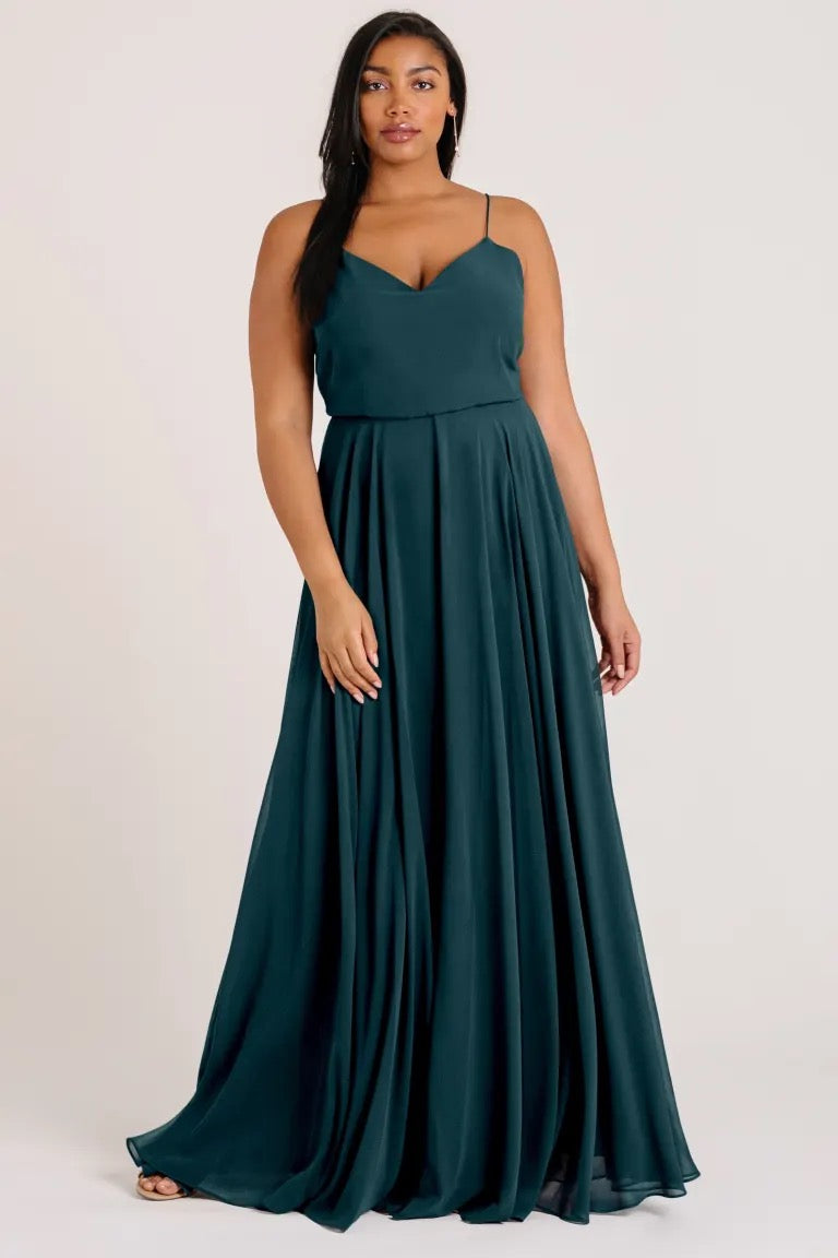 Woman posing in an elegant emerald green Inesse bridesmaid dress by Jenny Yoo with a V-neck from Bergamot Bridal.