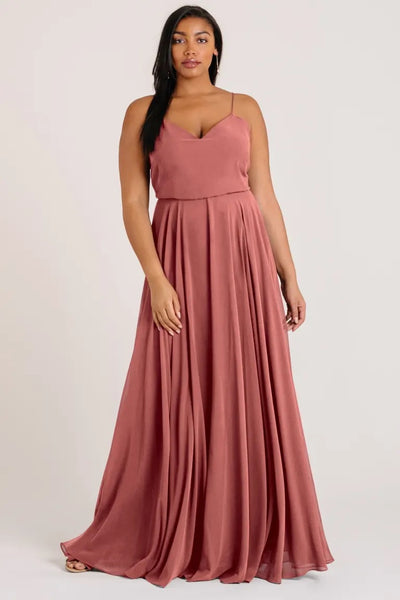 A woman in a flowing rose-colored V-neck Inesse - Bridesmaid Dress by Jenny Yoo evening gown, by Bergamot Bridal.