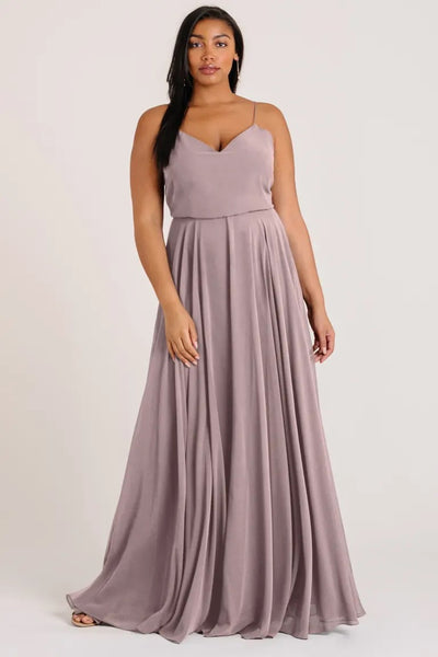 A woman in an elegant mauve Inesse bridesmaid dress by Jenny Yoo with a V-neck from Bergamot Bridal.