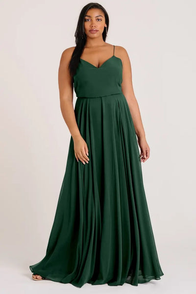 A woman in a green V-neck evening gown by Inesse - Bridesmaid Dress from Jenny Yoo posing for the camera.