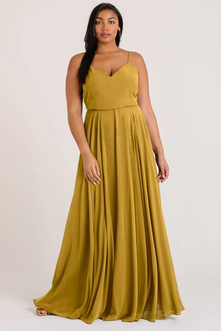 Woman in an elegant mustard-coloured Inesse - Bridesmaid Dress by Jenny Yoo with a flowing circle skirt from Bergamot Bridal.