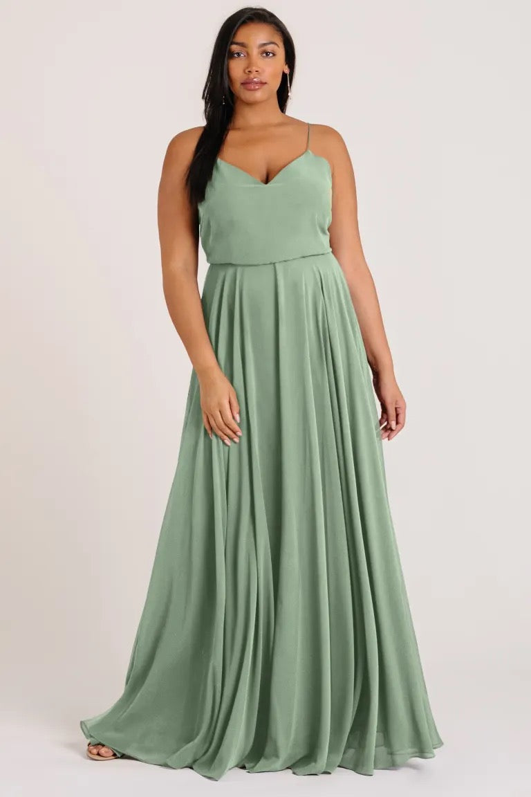 Woman in a green, Inesse chiffon bridesmaid dress by Jenny Yoo with a V-neck, standing confidently from Bergamot Bridal.
