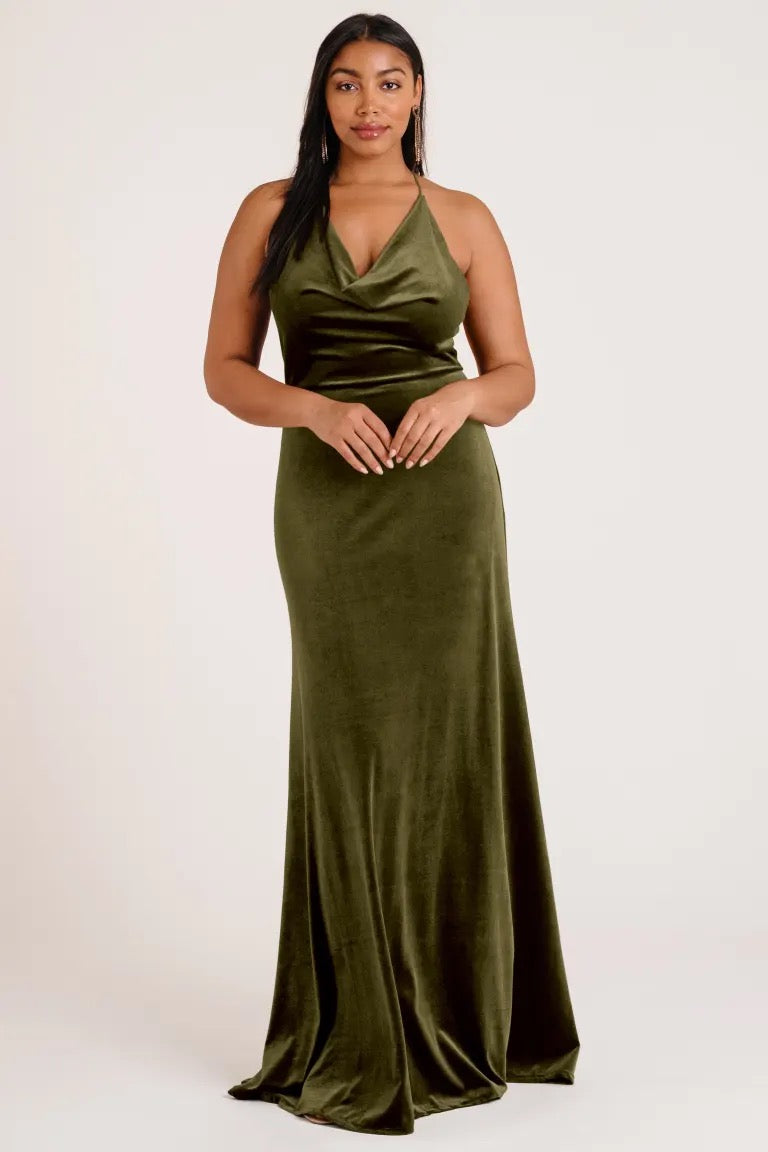 Woman in a Sullivan - Bridesmaid Dress by Jenny Yoo in olive green velvet with a cowl neckline, posing for the camera from Bergamot Bridal.