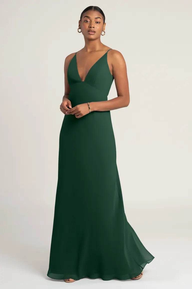 A woman in an elegant green evening gown, the Jude bridesmaid dress by Jenny Yoo with a flattering empire waist from Bergamot Bridal.