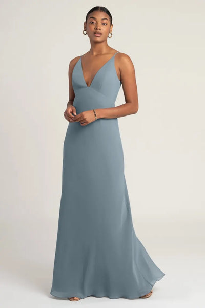 Woman in an elegant blue evening gown with an empire waist, wearing the Jude - Bridesmaid Dress by Jenny Yoo from Bergamot Bridal.