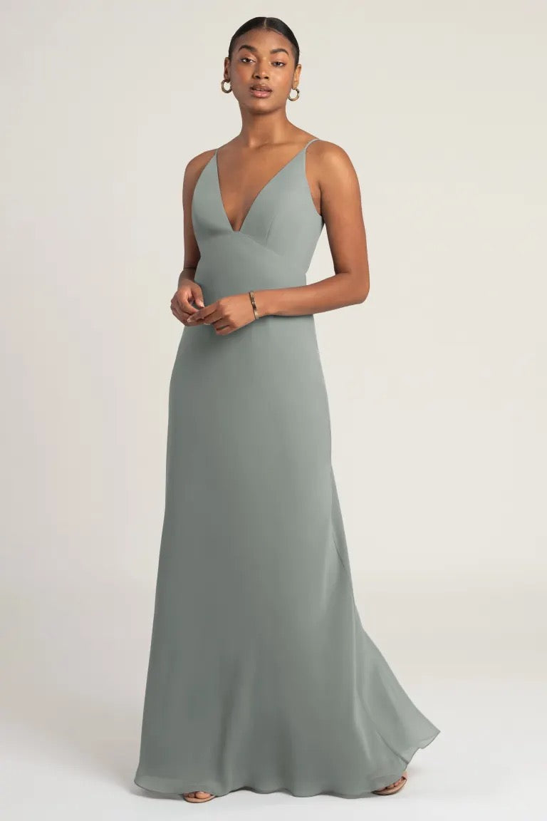 Woman posing in an elegant gray evening gown with empire waist, the Jude Bridesmaid Dress by Jenny Yoo from Bergamot Bridal.