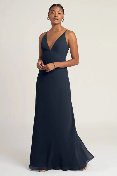 A woman in an elegant black evening gown with empire waist, posing against a neutral background wearing the Jude - Bridesmaid Dress by Jenny Yoo from Bergamot Bridal.