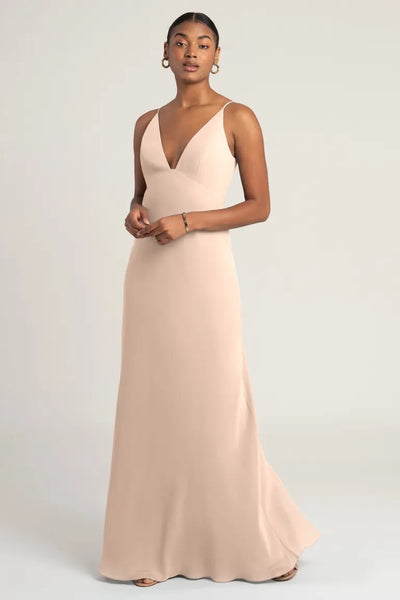 Woman in a beige chiffon slip Jude bridesmaid dress by Jenny Yoo, posing against a neutral background at Bergamot Bridal.