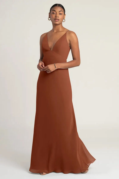 Woman posing in an elegant brown evening gown, the Jude Bridesmaid Dress by Jenny Yoo from Bergamot Bridal, with mix and match fabrications.