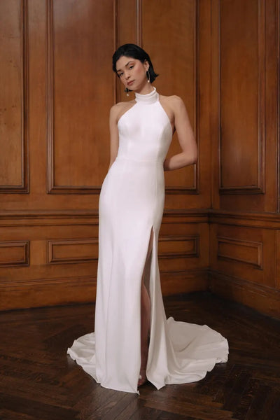 Woman in an elegant Jenny Yoo Wedding Dress with a mock neckline, posing against a wooden panel background from Bergamot Bridal.