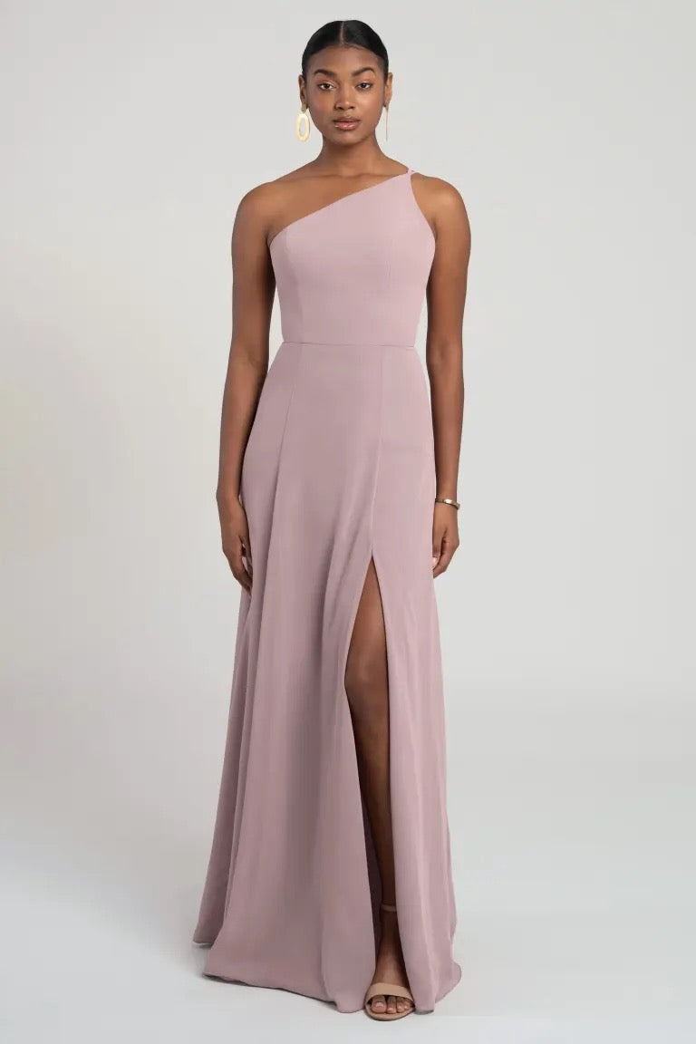 Woman posing in a flattering fit and flare silhouette, one shoulder chiffon bridesmaid dress with a thigh-high slit Kora - Jenny Yoo Bridesmaid Dress from Bergamot Bridal.