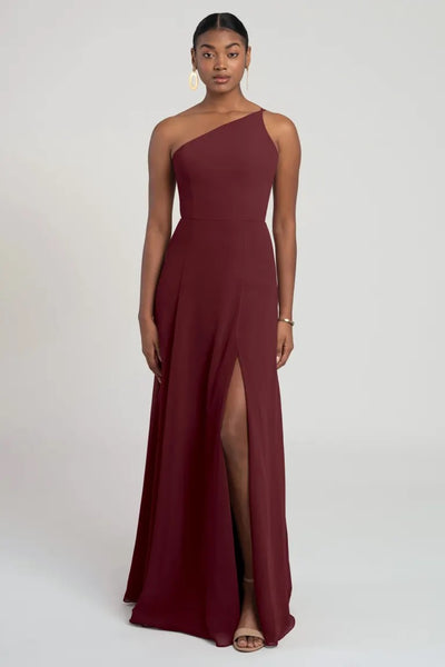 A woman in a modern look one-shoulder chiffon Kora - Jenny Yoo bridesmaid dress with a flattering fit and flare silhouette from Bergamot Bridal.